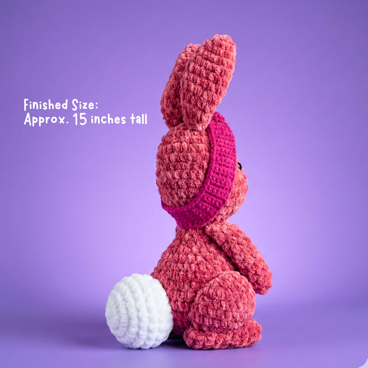 Crocheted pink bunny toy on a purple background with text indicating finished size.