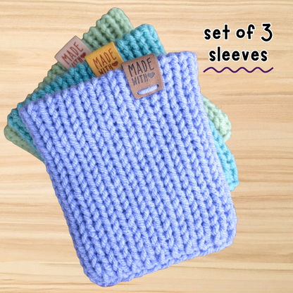 Set of three knitted sleeves with 'Made with Care' tags on a wooden surface