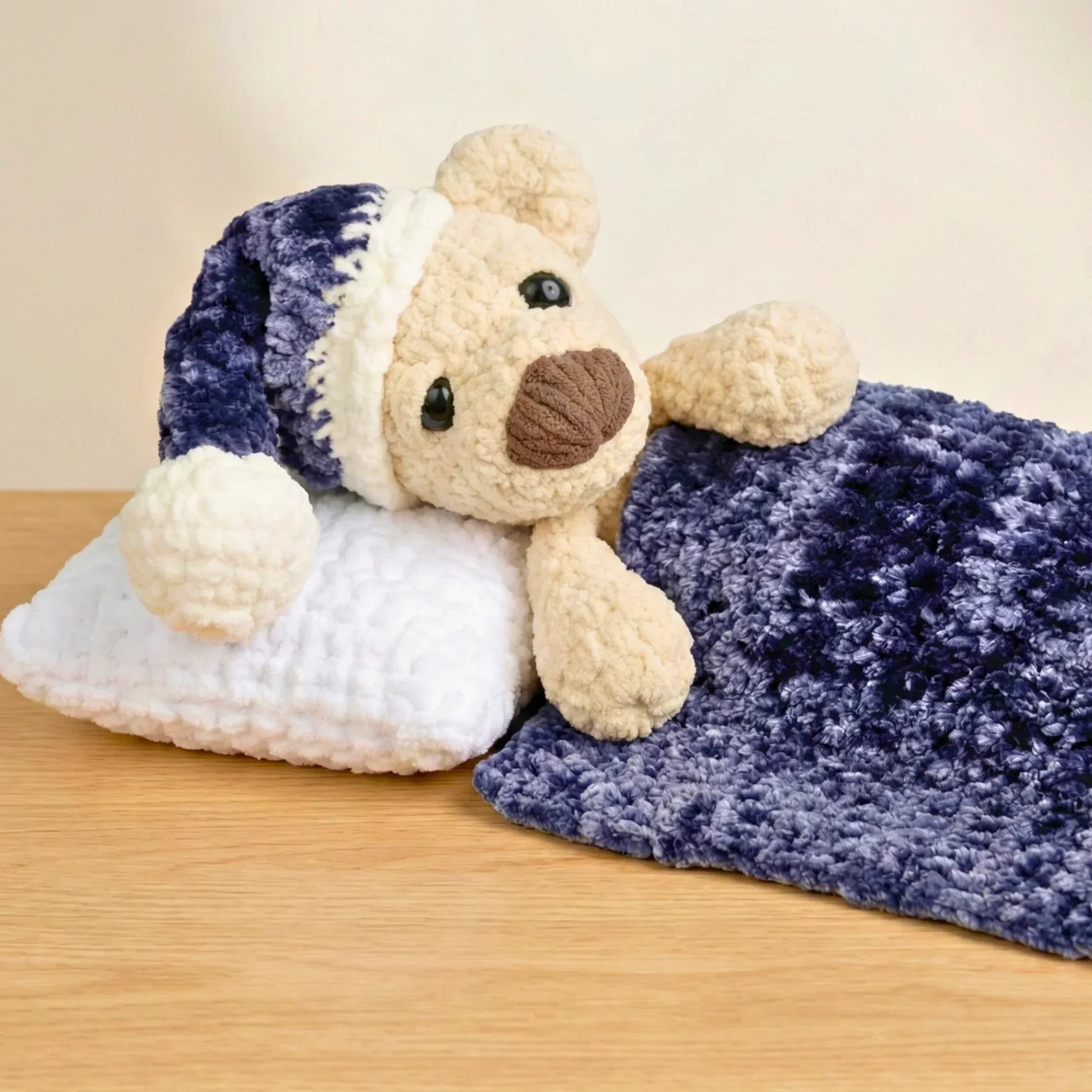 Crochet sleeping bear plush toy with nightcap, pillow, and blue blanket, amigurumi pattern