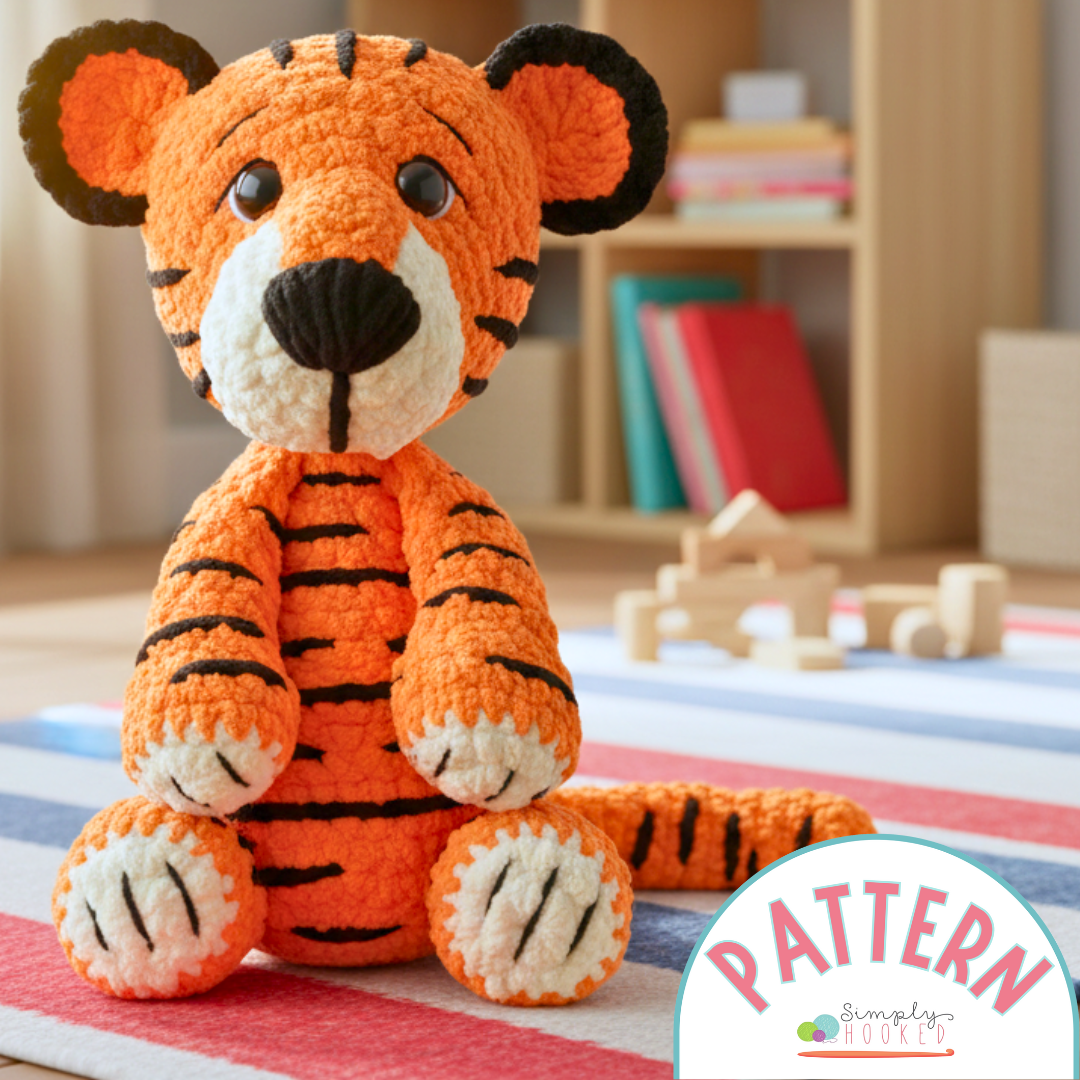 Crocheted tiger toy on a striped rug with 'Simply Hooked' pattern label.
