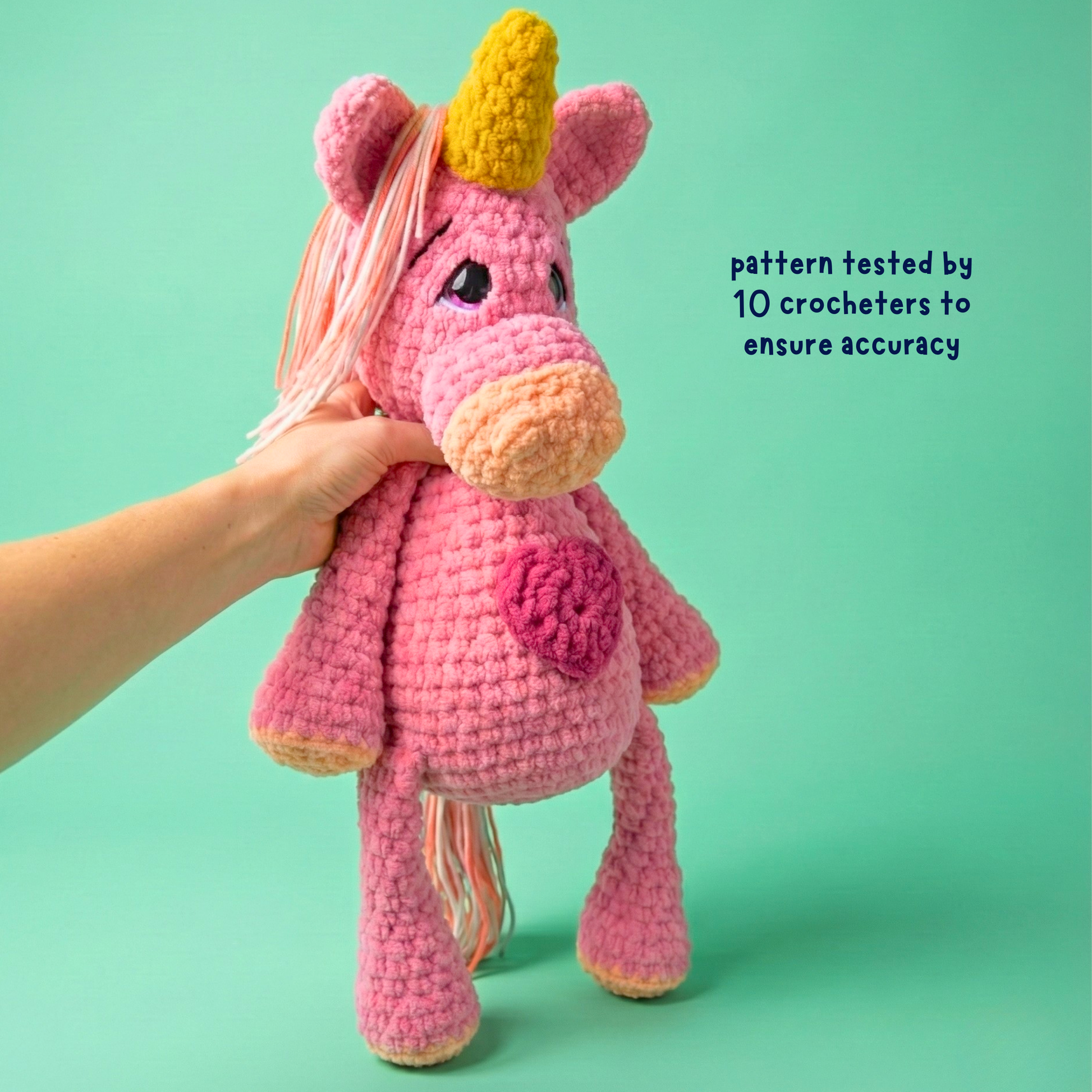 Pink crochet unicorn with a yellow horn on a green background