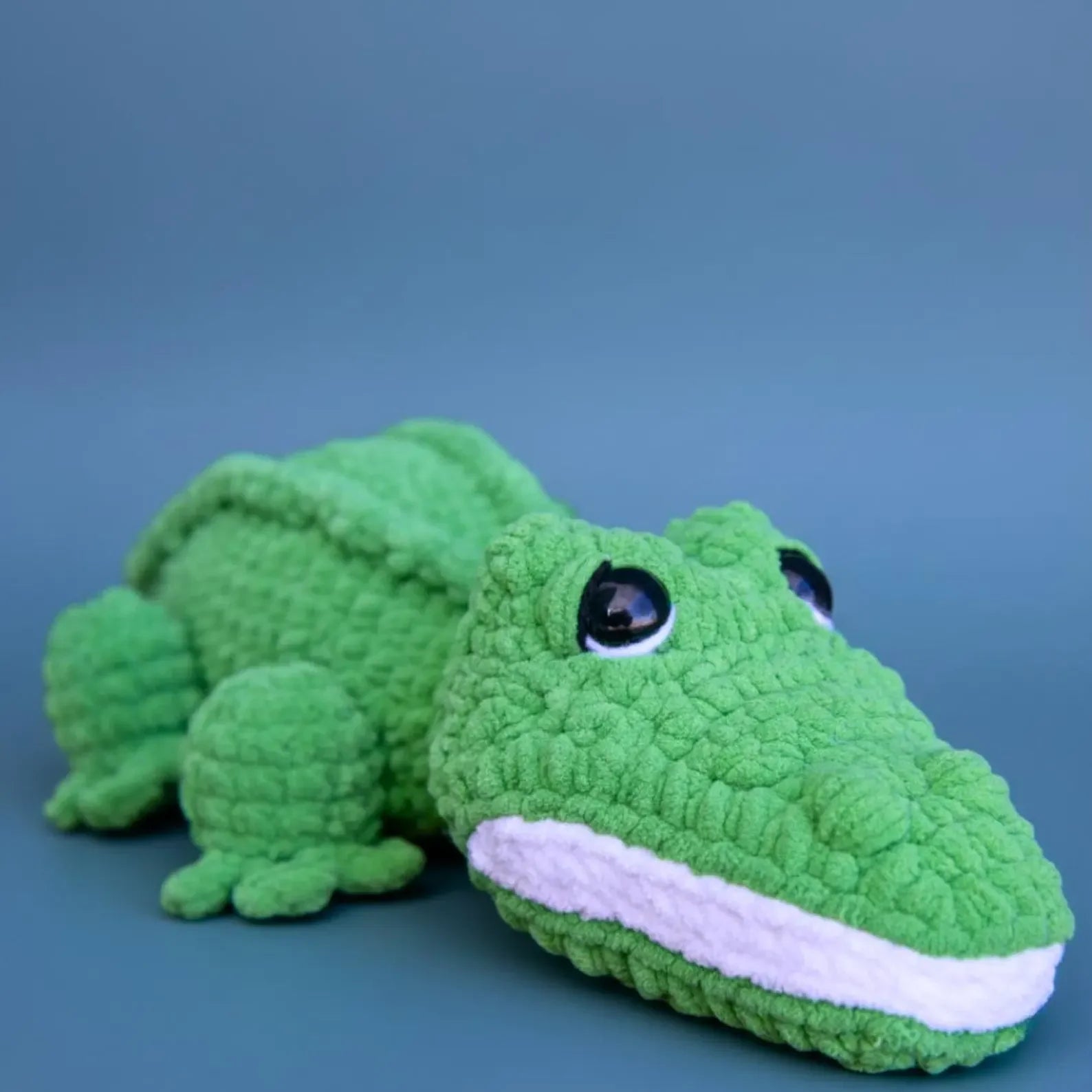 Green crocodile-shaped plush toy on a blue background