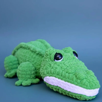 Green crocodile-shaped plush toy on a blue background