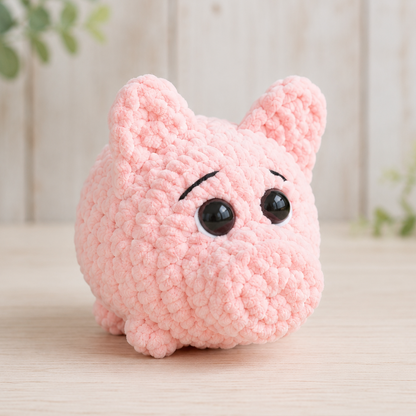 Pink crochet pig toy on a light wooden surface with a blurred natural background