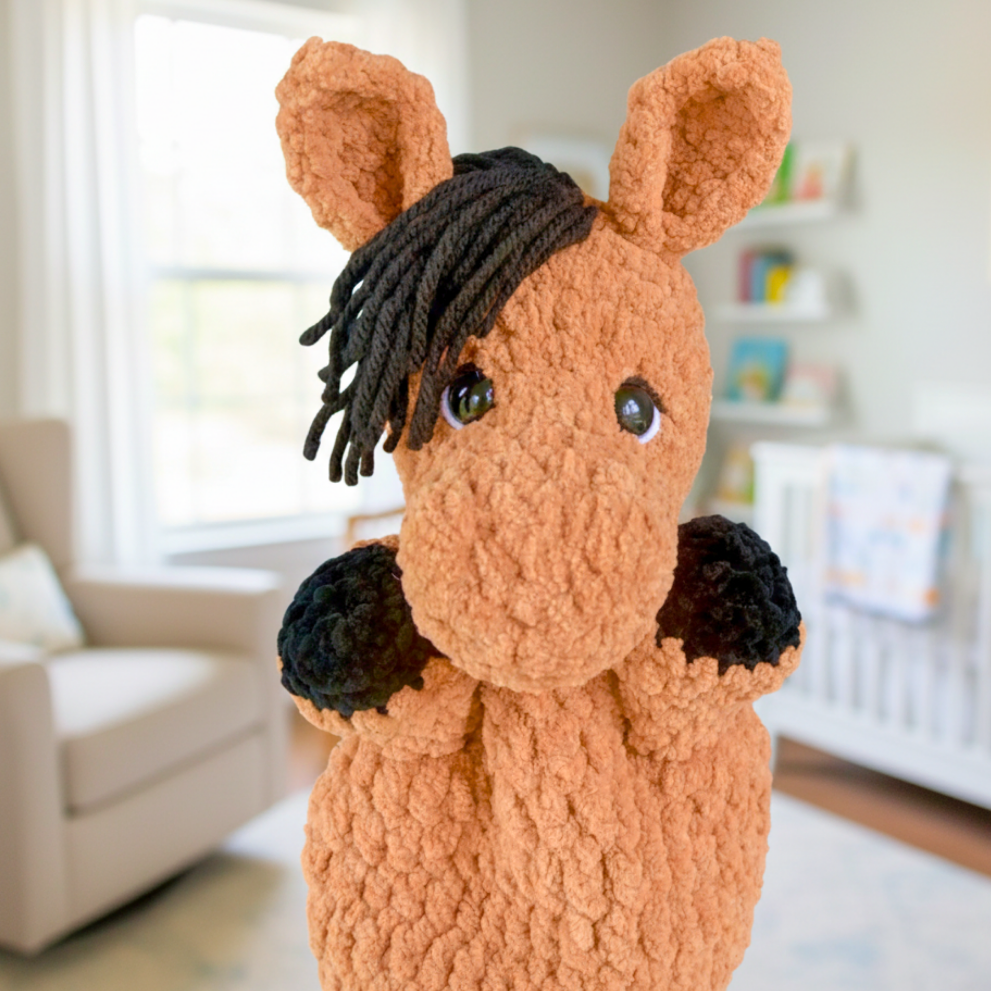 Close-up of a soft brown and black handmade horse plush toy in a cozy nursery room