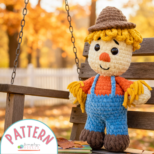 Crocheted scarecrow toy on a wooden swing with autumn background