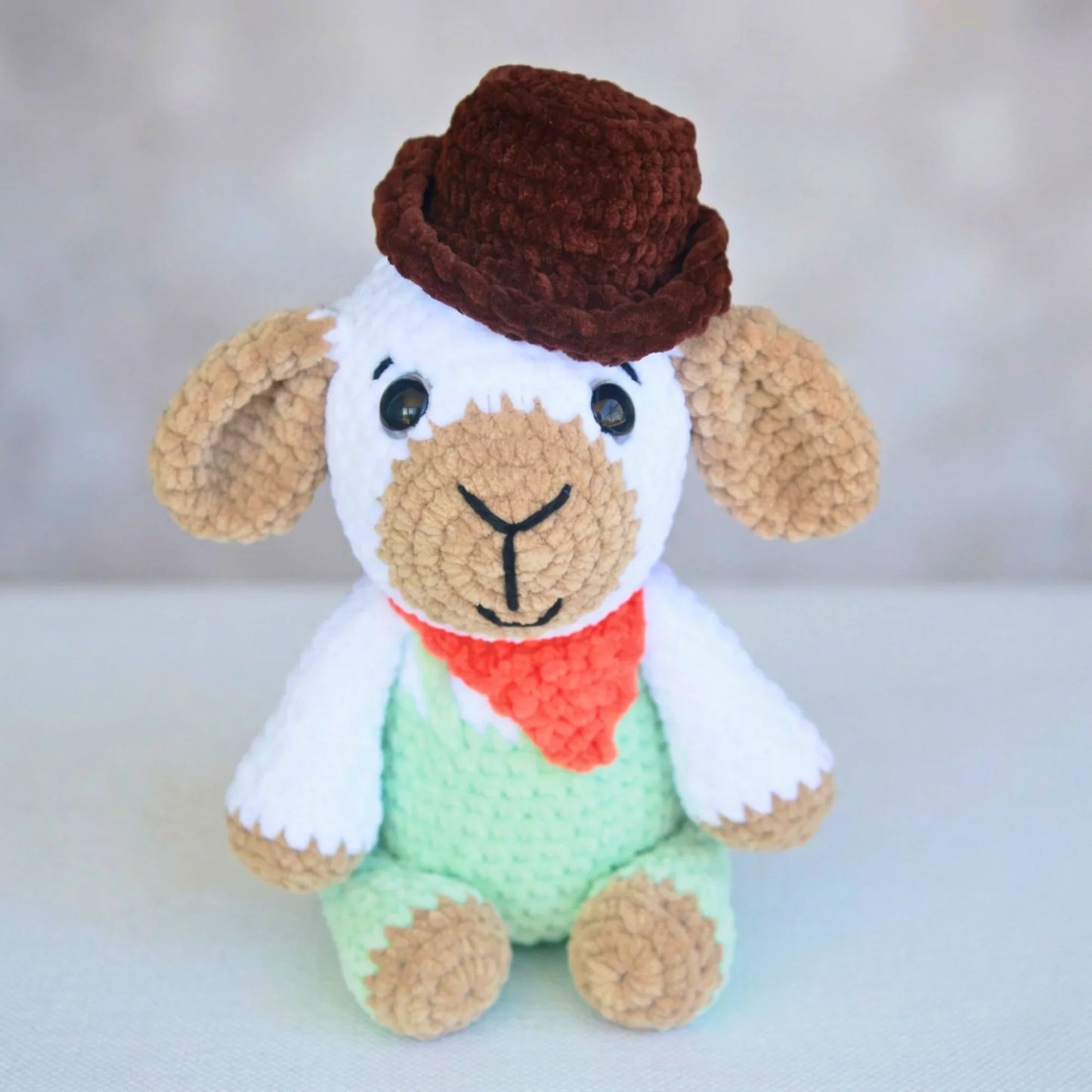 crochet plush lamb in mint overalls, brown hat, and red bandana amigurumi toy