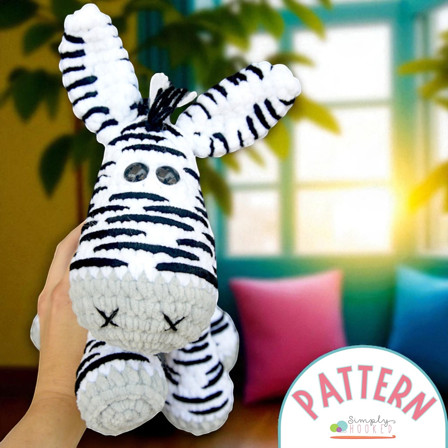 Hand holding a zebra plush toy with a blurred indoor background