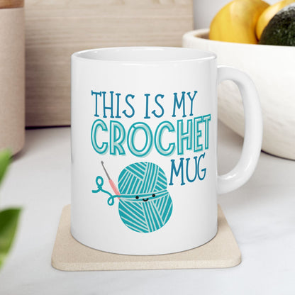 White mug with 'This is my crochet mug' text and yarn ball design on a coaster.