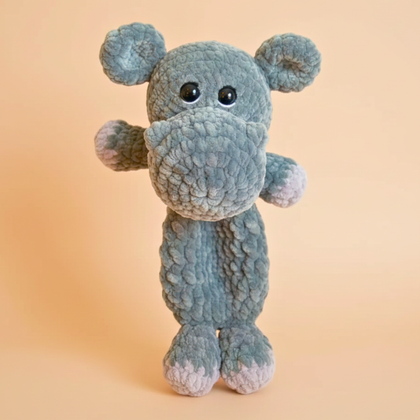 Gray plush stuffed hippopotamus toy with textured fabric and black eyes on beige background