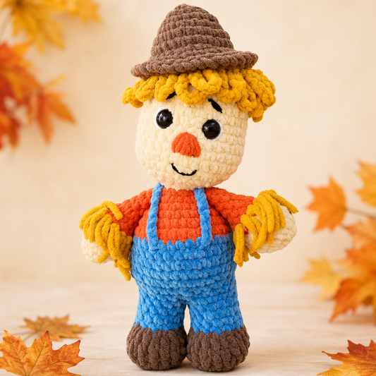 Crocheted scarecrow toy with autumn leaves on a light background